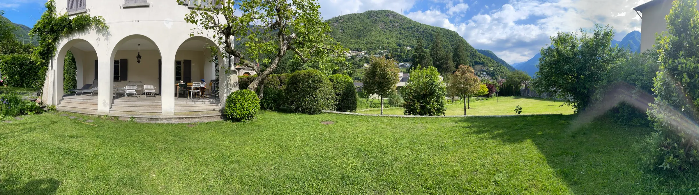 Panorama von Garten, Haus und umliegenden Bergen