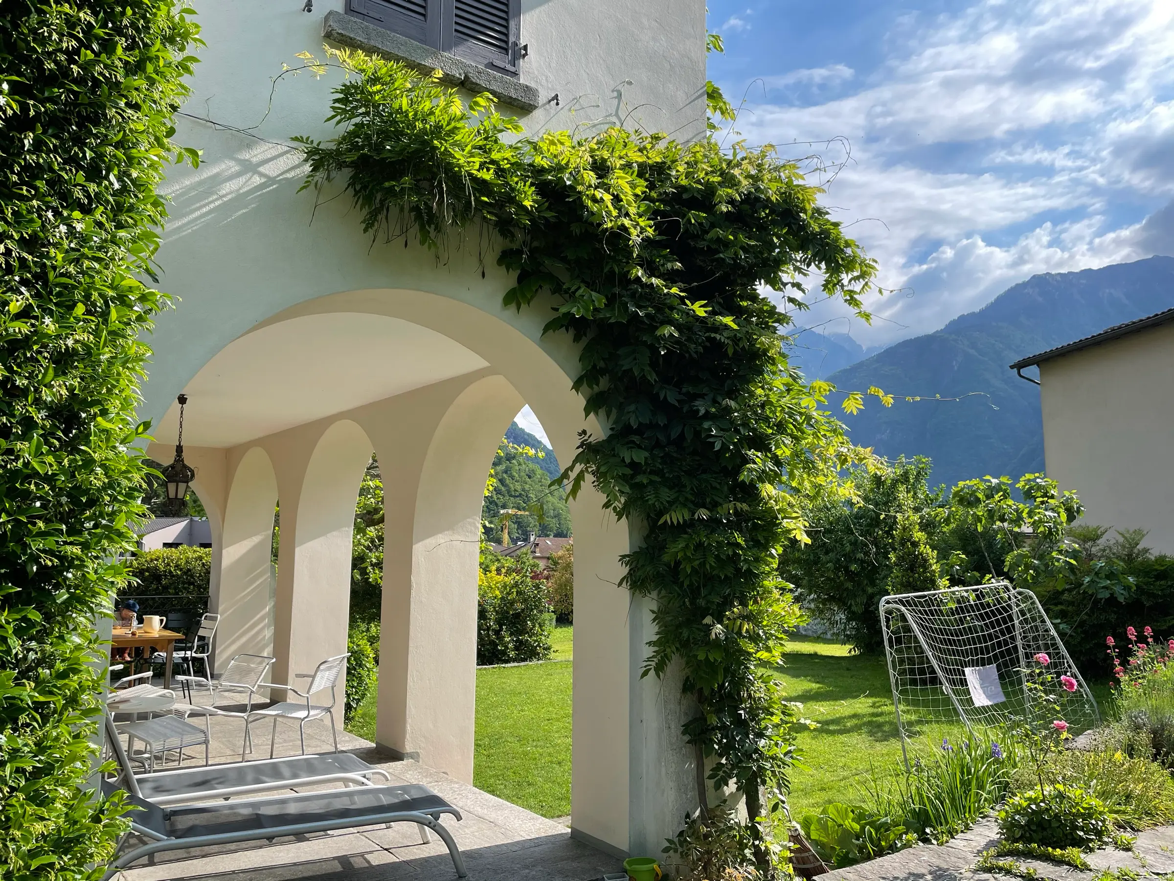 Überdachte Veranda mit Liegestühlen und Esstisch